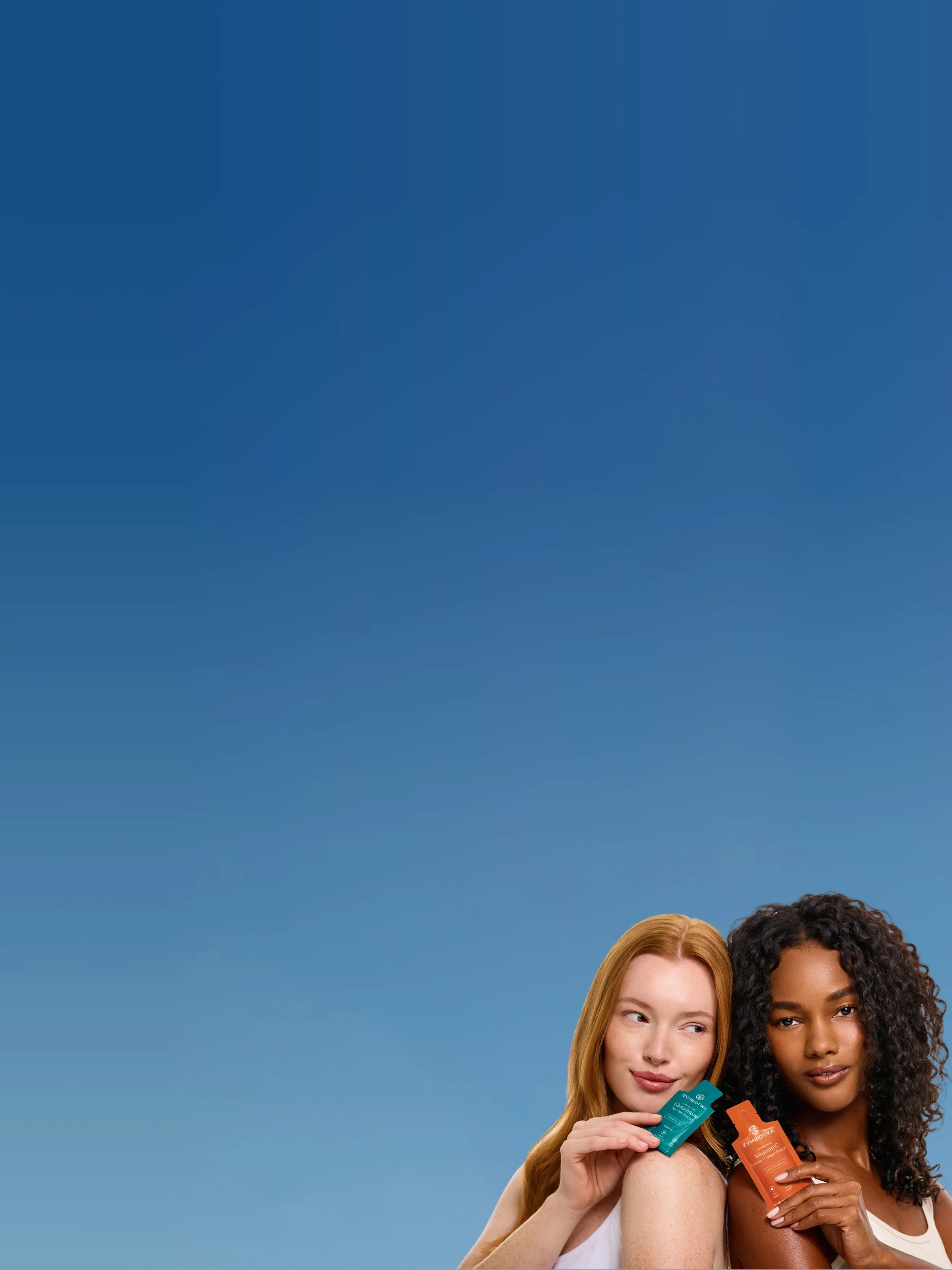 Two women hold Cymbiotika Liposomal Glutathione and Liposomal Vitamin C pouches against a blue sky